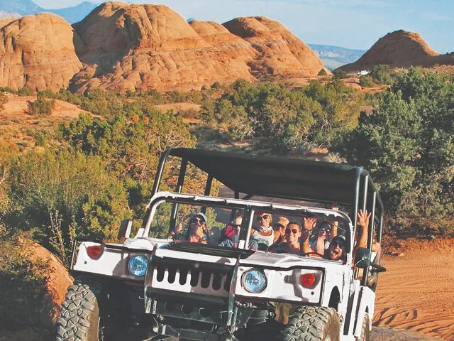 Eine Gruppe von Personen in einem Offroad-Fahrzeug beim Durchqueren des felsigen Geländes in Hell's Revenge.