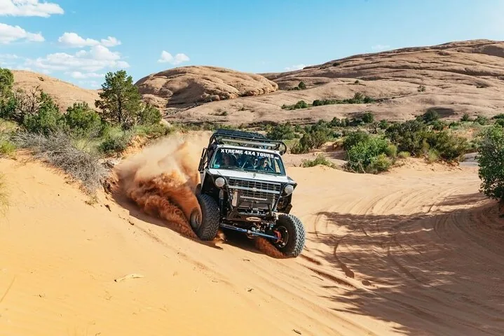 Offroad-Fahrzeug fährt durch eine sandige Gegend mit Wüstenlandschaft.