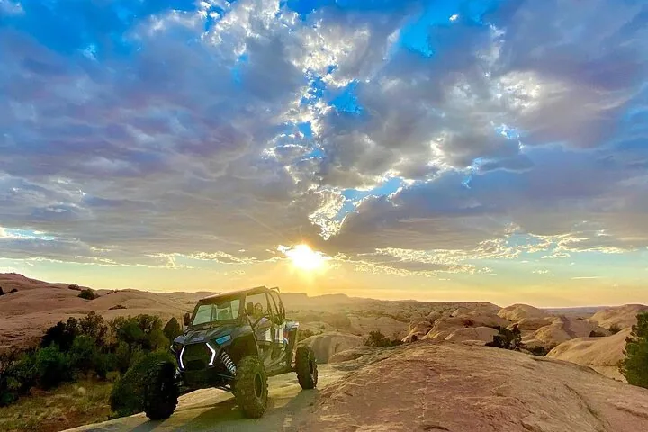 Ein blauer Polaris RZR Buggy, geparkt auf Slickrock bei einem wunderschönen Sonnenaufgang.