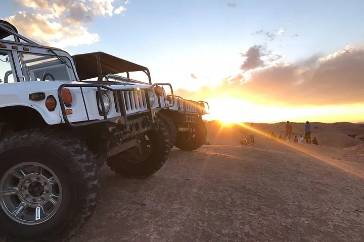 Zwei Offroad-Fahrzeuge, geparkt auf Felsen mit einem leuchtenden Sonnenuntergang im Hintergrund.
